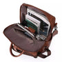 Sac à dos en similicuir marron ouvert avec livres, tablette et accessoires à l’intérieur