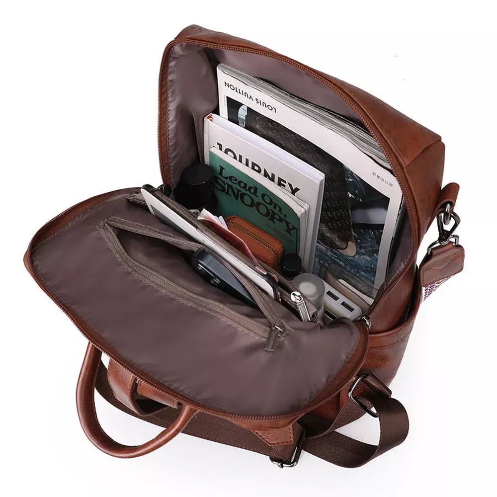Sac à dos en similicuir marron ouvert avec livres, tablette et accessoires à l’intérieur