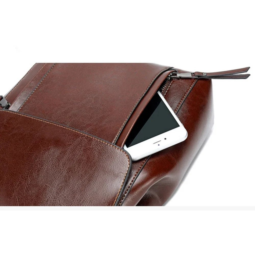 Sac à dos cuir marron avec poche zippée extérieure contenant un téléphone