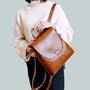 Femme en pull blanc et pantalon foncé tenant un sac à dos en similicuir brillant