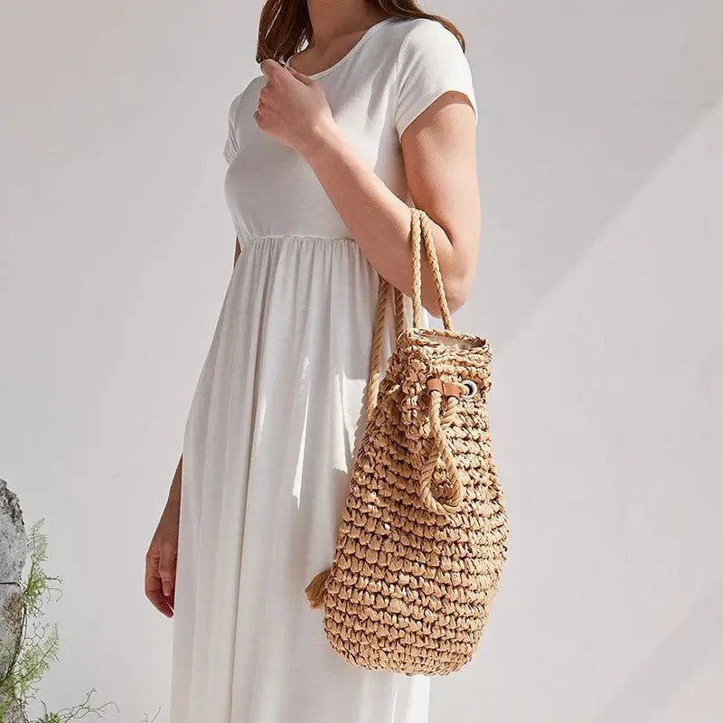 Femme portant une robe blanche avec un sac à dos en paille chic et tressée