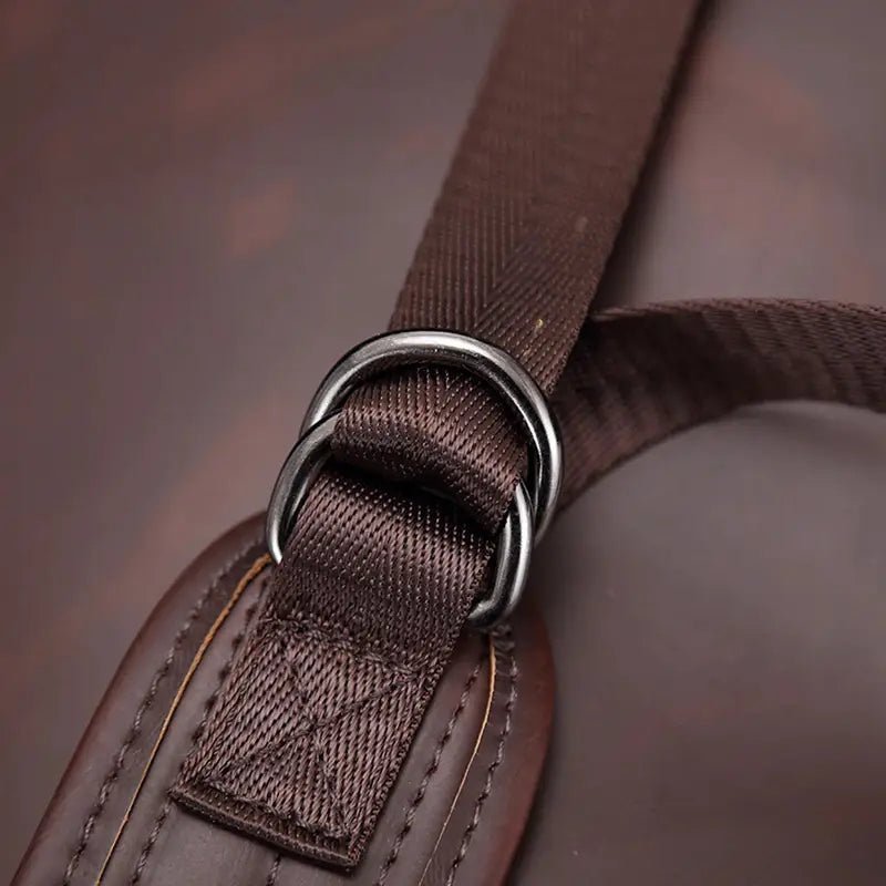 Sangle en tissu marron attachée à un coussin en cuir avec deux anneaux en métal