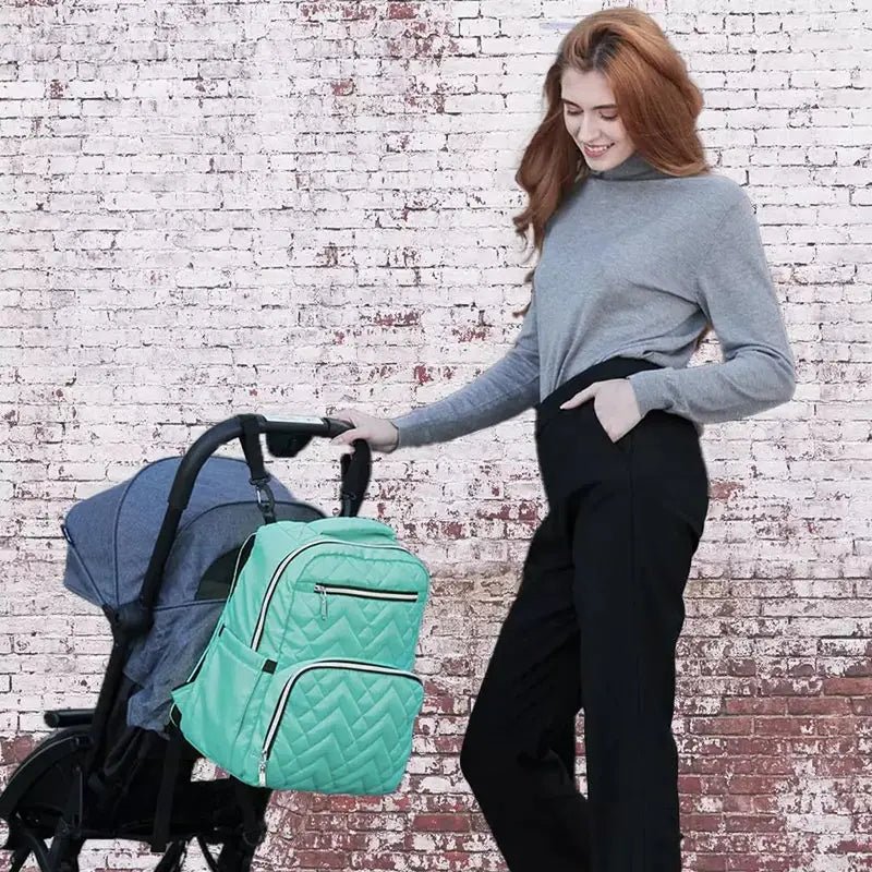 Femme en haut gris et pantalon noir poussant une poussette avec sac à langer isotherme menthe