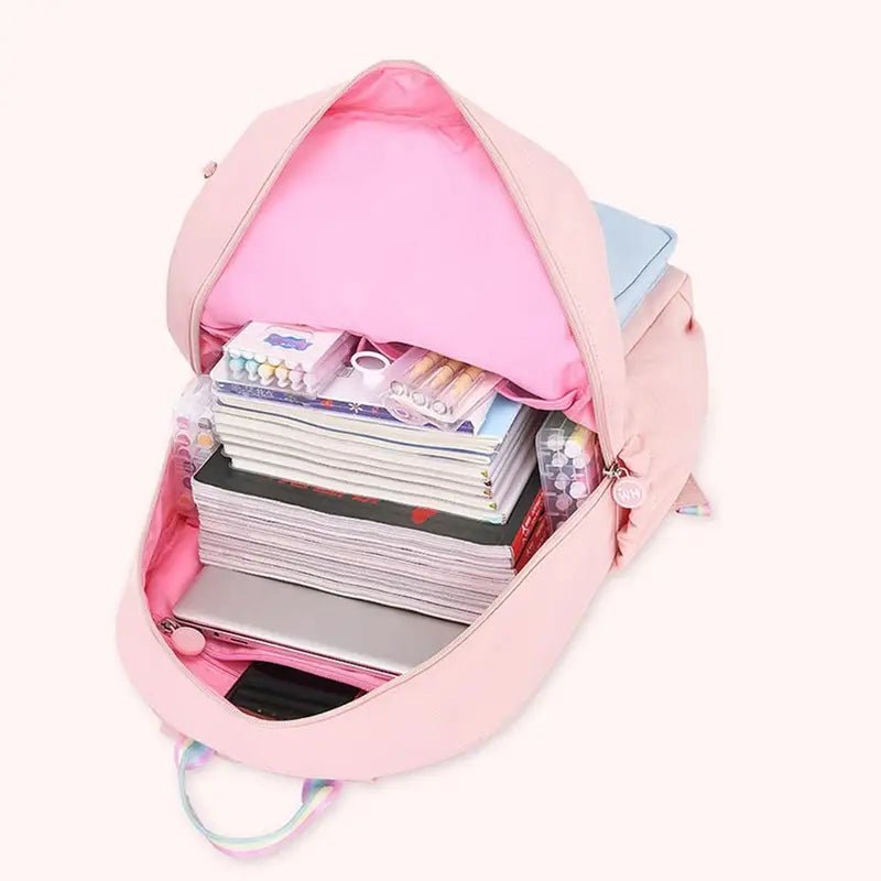 Sac à dos maternelle fille rose rempli de livres, ordinateur portable et fournitures scolaires