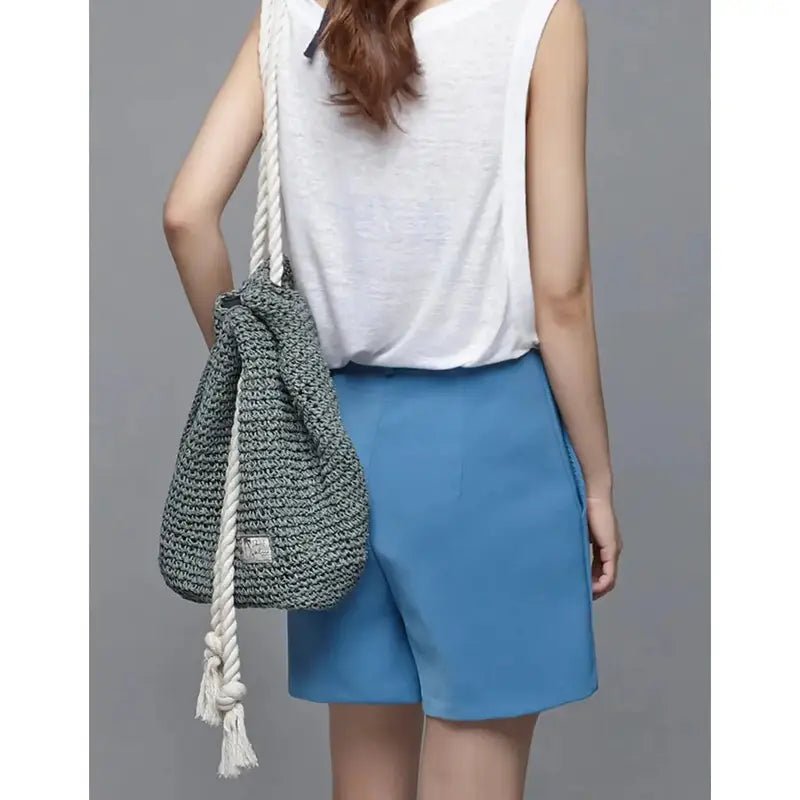 Femme portant un sac à dos paille vert en crochet avec une sangle en corde blanche