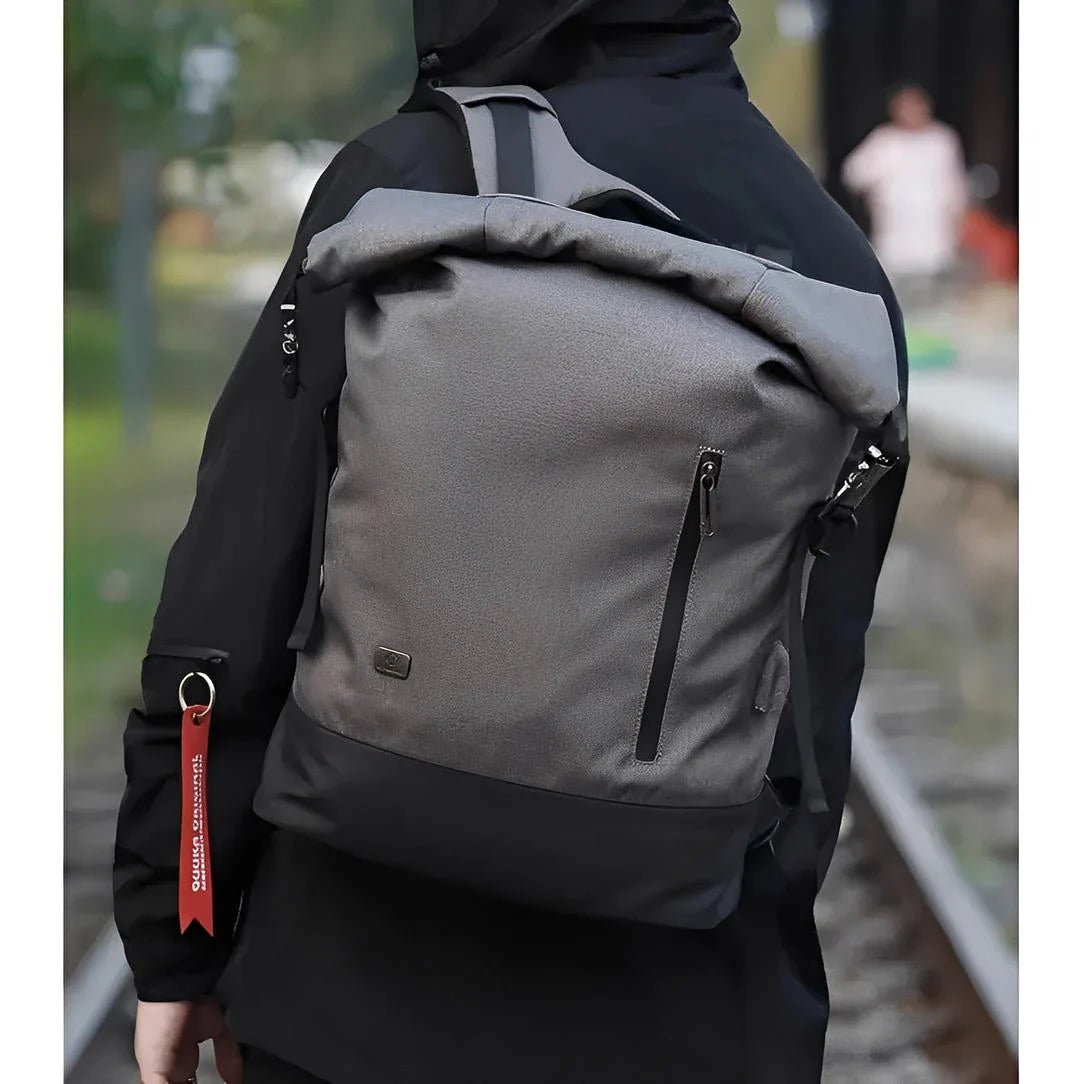 Sac à dos roll top homme gris et noir avec poche verticale et accessoire clé rouge