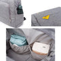 Sac à langer à dos en tissu gris avec compartiments, contenant un parapluie et autres objets